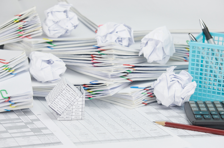 Bankruptcy of house and pencil with calculator on finance account have blue pen box and paper ball on step of paperwork as background.の写真素材