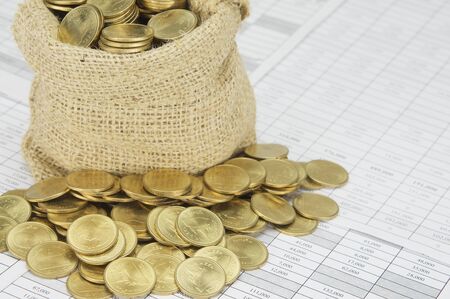 Close up stack of gold coins with brown sack of coins on finance account.の写真素材