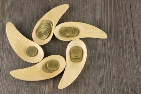 Gold coins in wooden spoon place as rowel on wood background.の写真素材