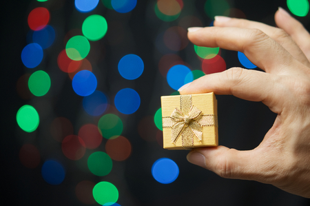 Hand of man pinch present have colorful bokeh as background.の写真素材