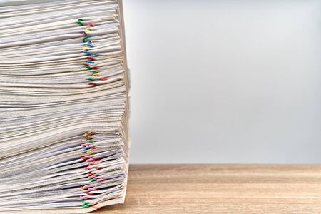 Pile of overload paperwork report of sale with colorful paper clip on wooden table with white...