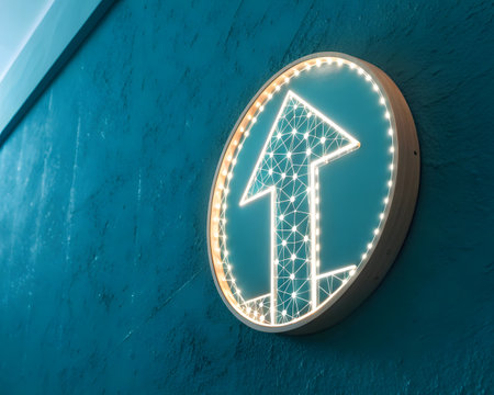 A close-up shot captures an illuminated arrow sign mounted on a blue textured wall, providing guidance and direction with its bright, modern design and circular shape.の素材
