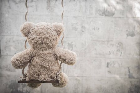 teddybear playing on a swing, photo taken from behindの写真素材