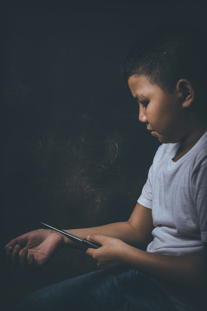scared and alone, young Asian child who is at high risk of being bullied, trafficked and abused considering ending his lifeの写真素材