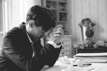 A stressed out business man holds his head in despair as he fears that he will have to file for bankruptcy or go into liquidationの写真素材