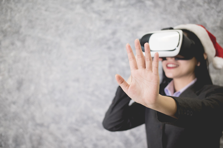 Young beautiful Asian girl wearing a festive Christmas hat while playing a virtual reality gameの写真素材