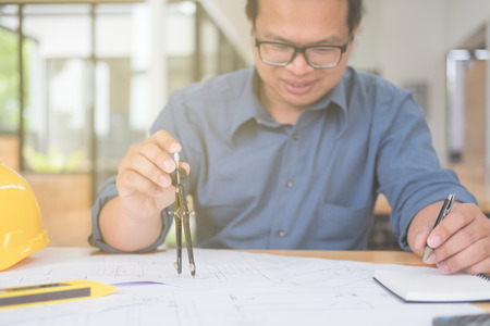 Architect or planner working on drawings for construction plans at a table