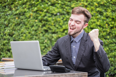 Looking for direction and inspiration, Portrait of happy young businessman sitting with laptop at coffee shopの写真素材