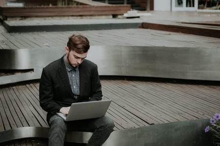 Looking for direction and inspiration, Portrait of happy young businessman sitting with laptopの写真素材