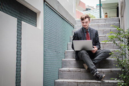Looking for direction and inspiration, Portrait of happy young businessman sitting with laptopの写真素材
