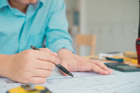 Architect or planner working on drawings for construction plans at a table