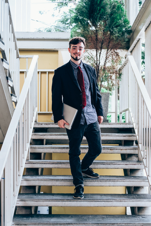Looking for direction and inspiration. Portrait of happy young businessman sitting with laptopの写真素材