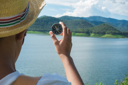 Hand with compass at mountain road at blue skyの写真素材