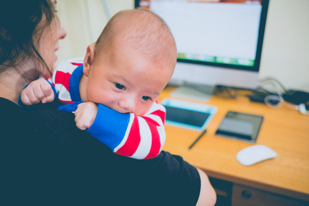 Working mother with a baby and her computer