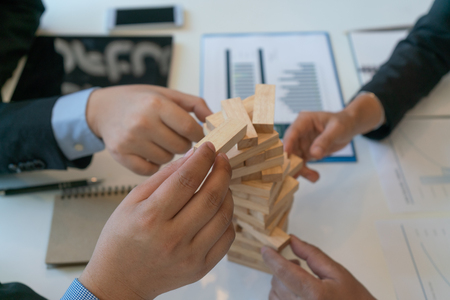 balancing the property sector in business, hands and a wooden houseの写真素材