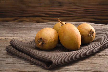 Sapodilla and brown fabric on rustic wooden tableの写真素材