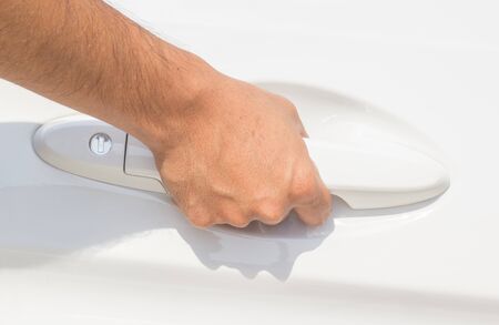 Male hand holding the door handle of white carの写真素材