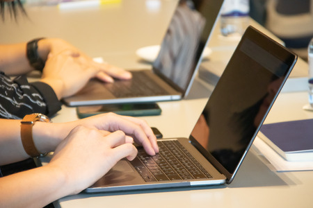 cropped view of businessman working with laptop computer at workplace in meeting room.の写真素材