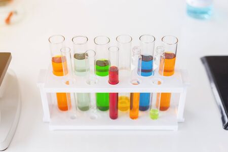 Test tubes with colorful liquids in holder on table in laboratory.
