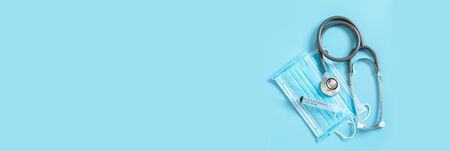 Medical stethoscope syringe and hygienic mask  protective virus on blue background, top view, banner lay out.の写真素材