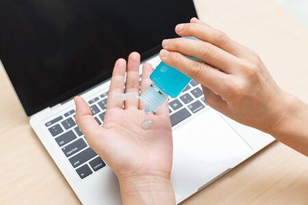 close up hand using sanitizer gel for hand hygiene coronavirus prevention before work with laptop at home.の写真素材