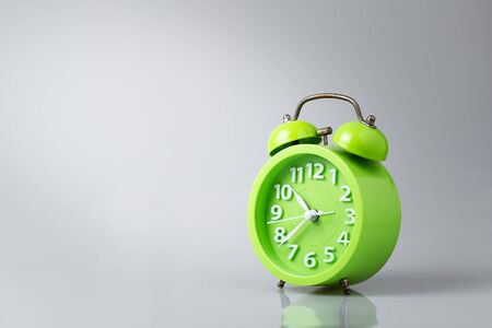Green analog alarm clock gray background with light and shadow, copy space.の写真素材
