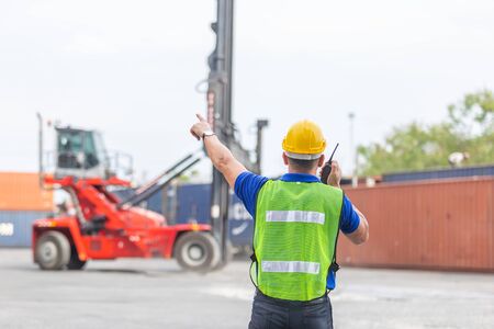 Foreman using radio communication control loading containersin shipping yard, for logistics and...