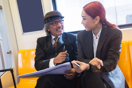 asian businessman and businesswoman meeting teamwork with laptop and travel bag on electric train...