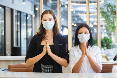 woman hotel receptionist wearing medical mask greeting thailand style.の写真素材