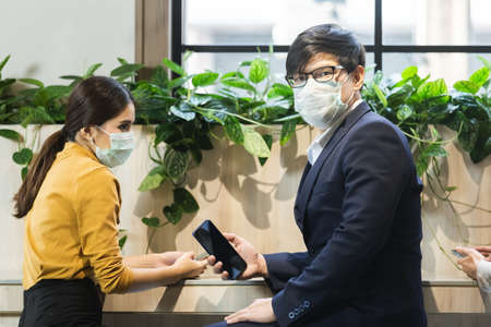asian business people with wearing hygienic mask prophylactic manager talking in meeting work room planning.の写真素材