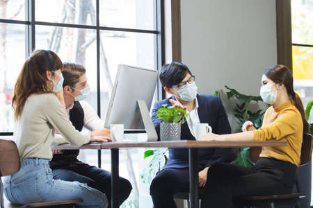 Group of business people with wearing hygienic mask prophylactic manager talking in meeting work room planning.の写真素材