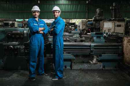Engineer men wearing uniform safety workers perform maintenance in factory working machine lathe...