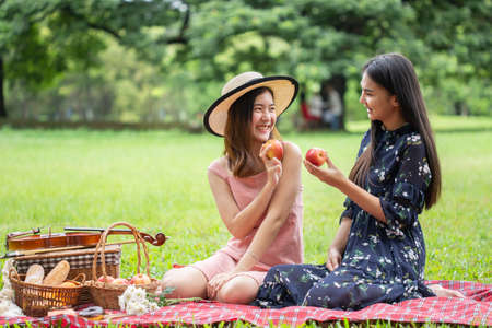 asian two young women are sitting in a picnic happy in garden.の写真素材