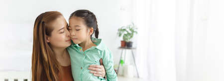 Asian mother and daughter embrace and happily kiss their cheeks with love. family concept.の写真素材