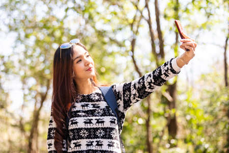Happy woman selfie take photo with smartphone travel in forest.の写真素材