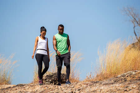 African-american couple in sportswear strolling in field on mountains.