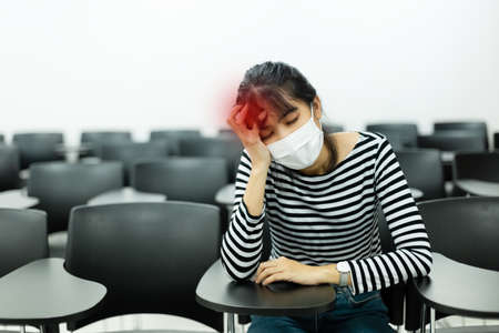 asian young woman with wearing hygienic mask prophylactic have symptoms sick, headache sitting in meeting room.の写真素材
