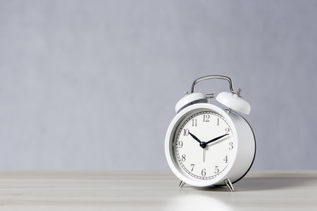 White retro analog alarm clock on table gray background with light and shadow, copy space.の写真素材