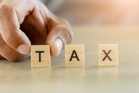 Close up hand touch wooden block with word tax, pay and debt, business and finance conceptの写真素材