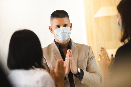 business man wearing medical mask greeting thailand style instead of handshake for prevent infection...