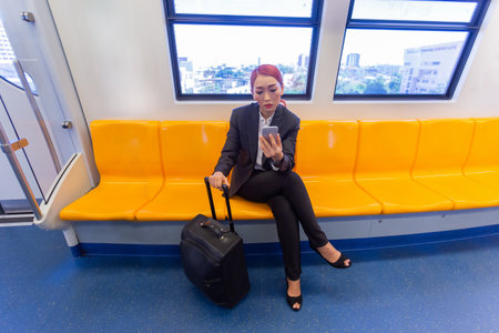 asian business female using smartphone in corridor at BTS train.