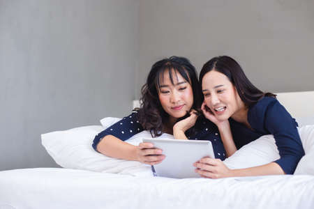 asian young woman using tablet relax working and shopping online on bedroom in hotel. online work leisure day.の写真素材