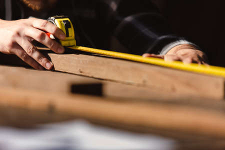 carpenter man using measuring tape looking wood size at workspace. craftsman profession in wood factory.の写真素材