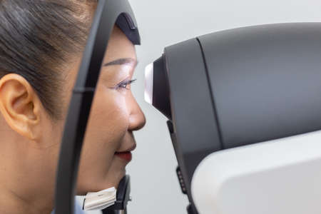 Close up face of middle aged asian woman examining eyesight modern machine equipment in clinic.の写真素材