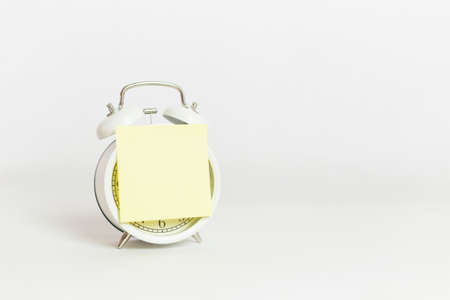 yellow note stick on white alarm clock white background.