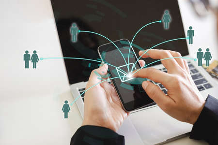 close up hand of woman using smartphone sending message from E-mail to other people with network laptop background. contact informational concept.の写真素材