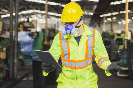 Man engineer wearing safety uniform with gloves and gas mask and taplet.の写真素材