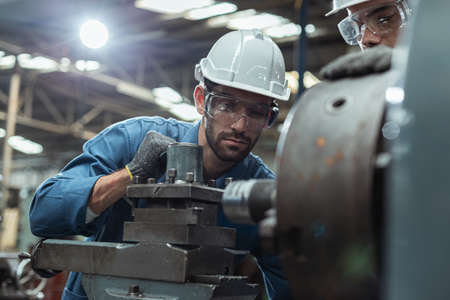 Engineer men wearing uniform safety in factory working machine lathe metal.