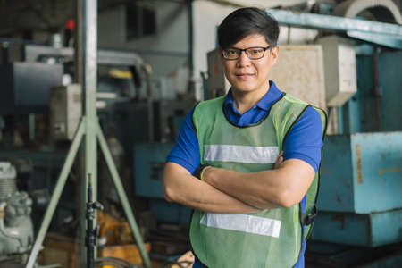 portrait of asian man engineering standing at factory with his arms crossed and looking at camera.の写真素材