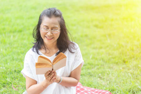 asian women reading book in garden.の写真素材